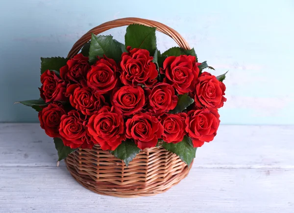 Ramo de rosas rojas en cesta sobre fondo de madera —  Fotos de Stock