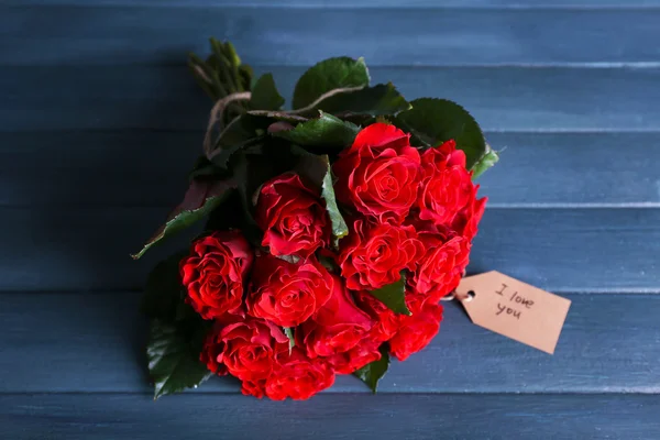 木製の背景にタグに赤いバラの花束 — ストック写真