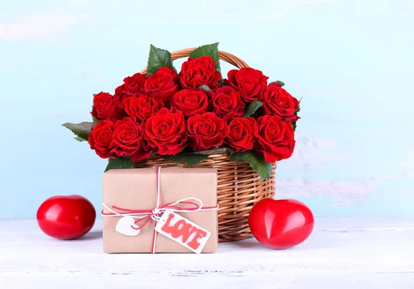 Strauß roter Rosen im Korb mit Geschenkbox auf Holzgrund — Stockfoto