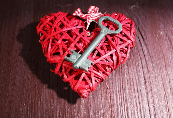 Key on wicker decorative heart on wooden background — Stock Photo, Image