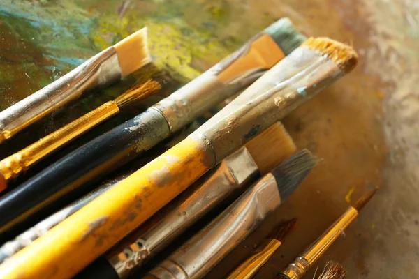 Different brushes on wooden palette — Stock Photo, Image
