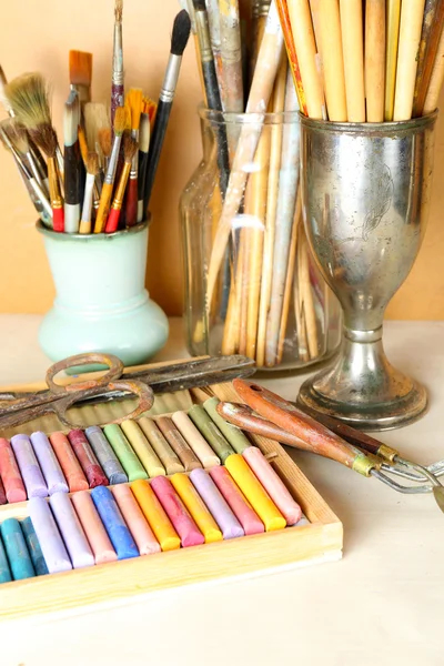Paintbrushes com pastéis de giz coloridos em caixa no fundo de madeira — Fotografia de Stock
