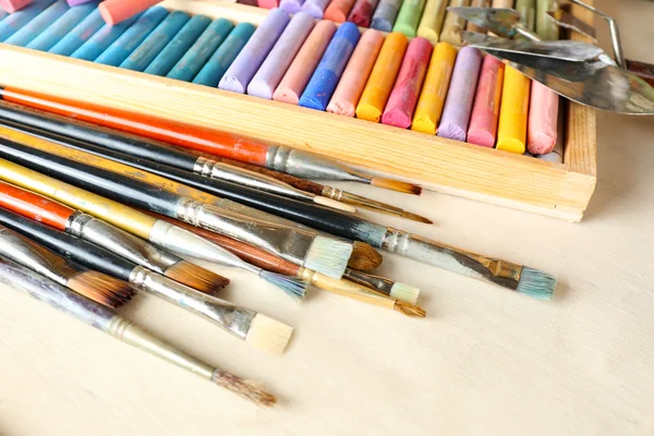 Paintbrushes with colorful chalk pastels in box on fabric background — Stock Photo, Image