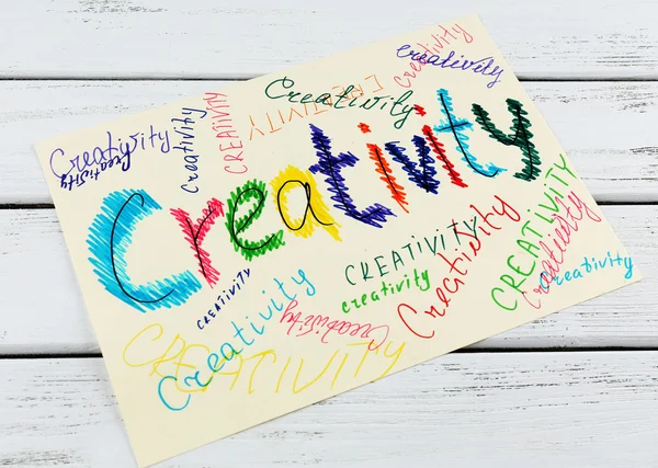 Ordet kreativitet på papper på trä bakgrund — Stockfoto
