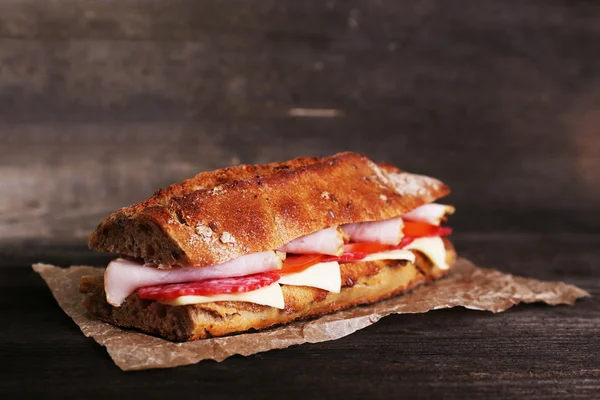 ハムとチーズの木製の背景紙の上の新鮮でおいしいサンドイッチ — ストック写真