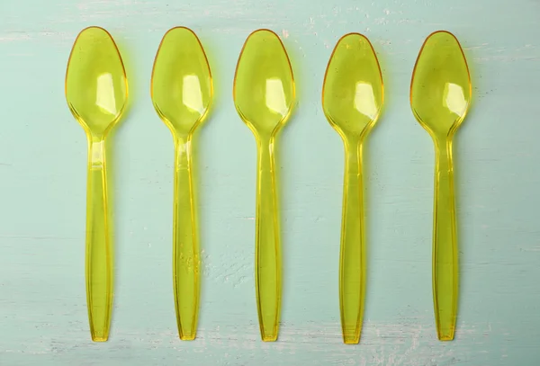 Plastic spoons on wooden background — Stock Photo, Image