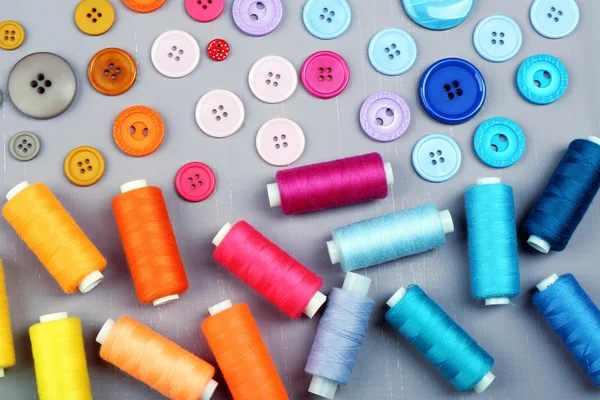 Botones coloridos e hilos de coser sobre fondo de madera — Foto de Stock