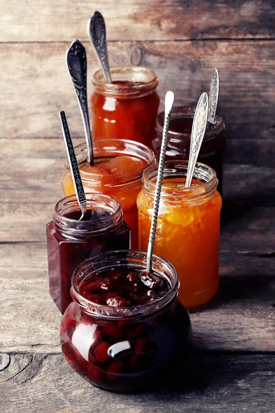 Gläser mit schmackhafter Marmelade auf hölzernem Hintergrund — Stockfoto