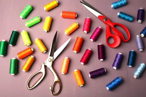 Filati per cucire multicolore con forbici su fondo di legno — Foto Stock