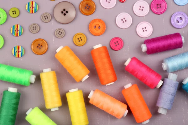 Colorful buttons and sewing threads on wooden background — Stock Photo, Image