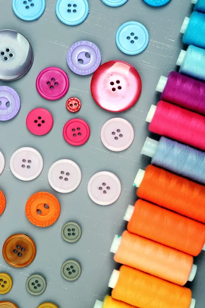 Botões coloridos e linhas de costura em fundo de madeira — Fotografia de Stock