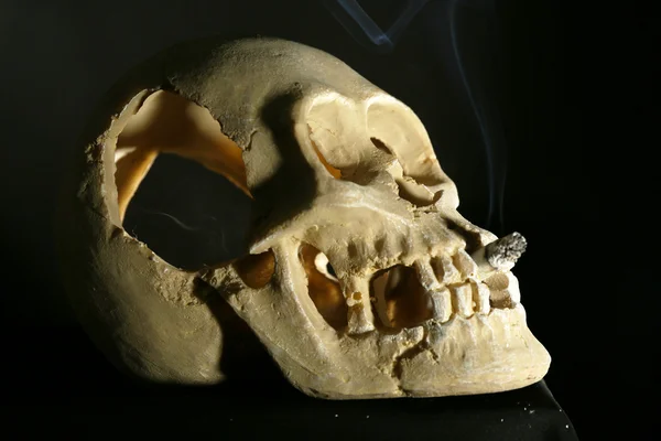 Fumar scull humano com cigarro em sua boca no fundo escuro — Fotografia de Stock