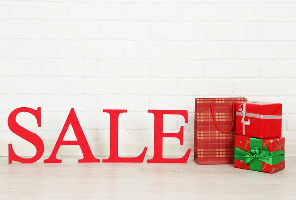 Verkoop met geschenken op verdieping op lichte achtergrond — Stockfoto