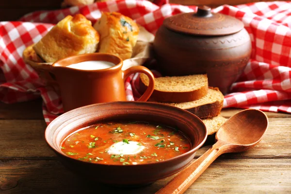 Ukrainische Rote-Bete-Suppe - Borschtsch in Schüssel und Topf, auf Serviette, auf Holzgrund — Stockfoto