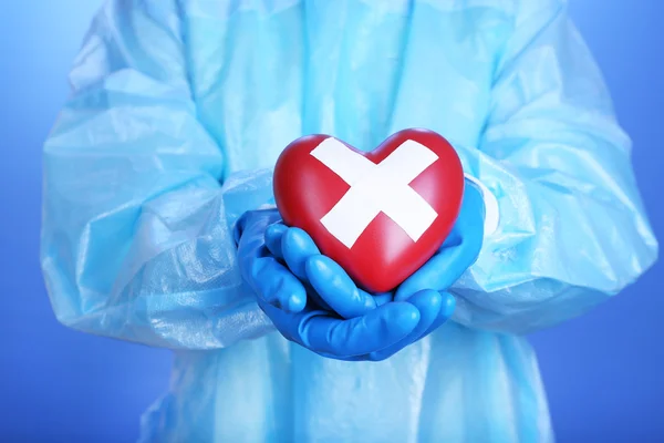 Médico segurando coração decorativo no fundo azul — Fotografia de Stock