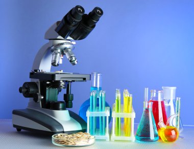 Mikroskop, tanecikler ve test tüpleri masada, renk arkaplanında