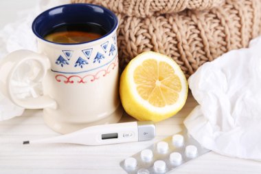 Hot tea for colds, pills and handkerchiefs on table close-up clipart