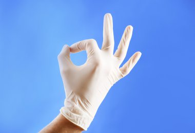 Doktor elinde mavi arka plan üzerinde steril eldiven