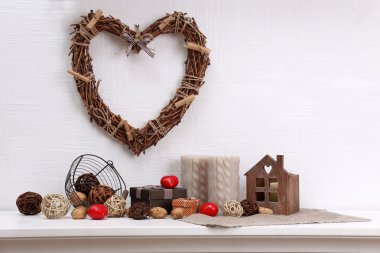 Raf ve beyaz duvar arka plan üzerinde hasır kalp ve tasarım detayları ile romantik natürmort