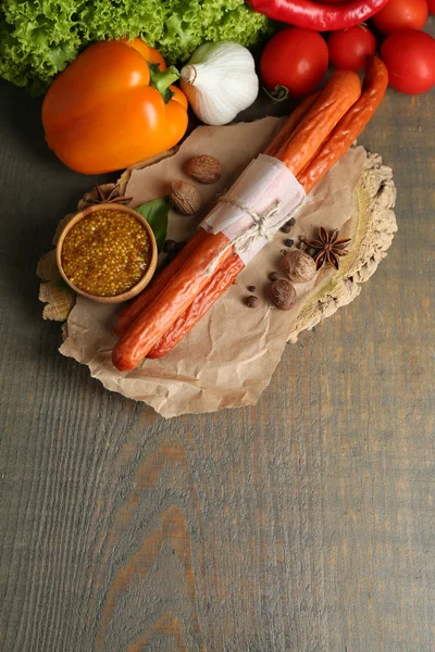 Composition of smoked thin sausages, mustard in bowl and spices on cutting board, on wooden background — Stock Photo, Image