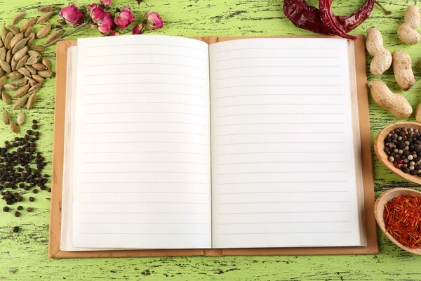 Specerijen met recept boek op kleur houten tafel achtergrond — Stockfoto