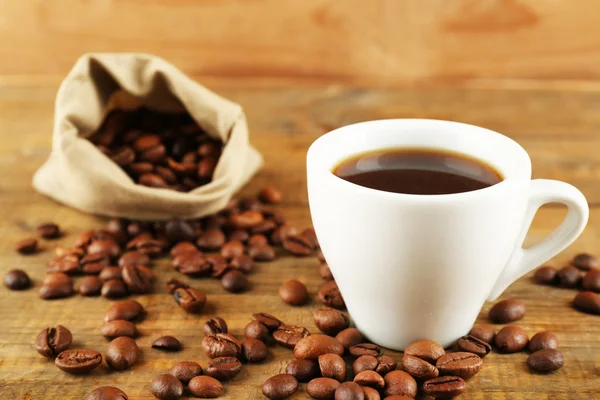 Xícara de café com feijão em fundo de madeira rústica — Fotografia de Stock