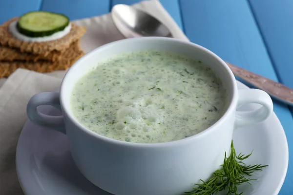 Cucumber soup in bowl on color wooden planks background — Stock Photo, Image