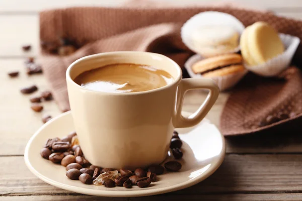 Mjuka färgglada macaroons och kaffe i mugg på träbord bakgrund — Stockfoto