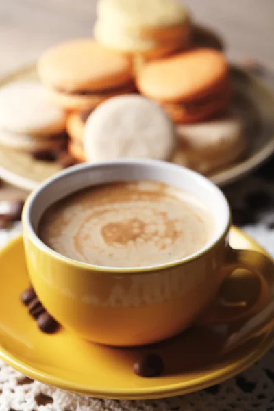 Zachte kleurrijke bitterkoekjes en koffie in een mok op houten tafel achtergrond — Stockfoto