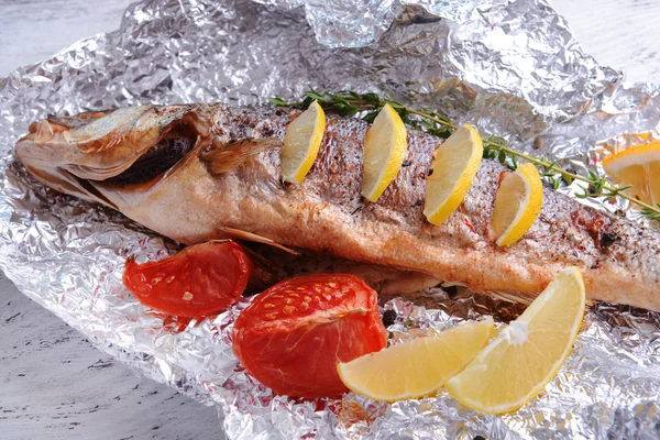 Tasty baked fish in foil on table close-up — Stock Photo, Image