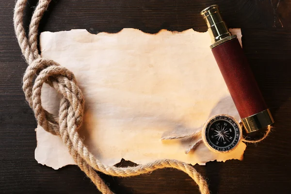 Marine still life spyglass, compass rope and sheet of paper on wooden background — Stock Photo, Image