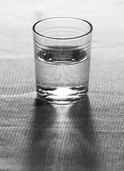 Vaso de agua mineral limpia sobre fondo de tela de arpillera — Foto de Stock