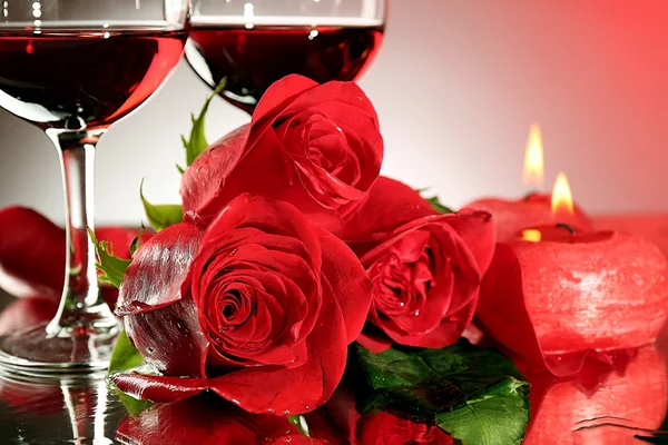 Kompozycja z czerwonego wina w okulary, czerwona róża i ozdobny serce na kolorowe tło — Zdjęcie stockowe