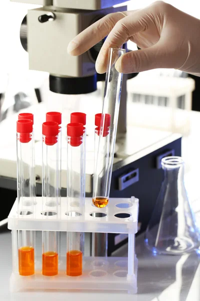 Assistant main dans les gants faire des analyses en laboratoire avec microscope sur fond blanc — Photo