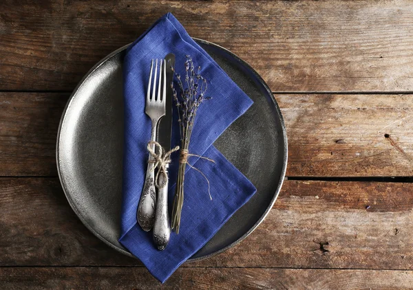 Silverware tied with rope on metal tray with colorful napkin and dried flower on wooden planks background — Stock Photo, Image