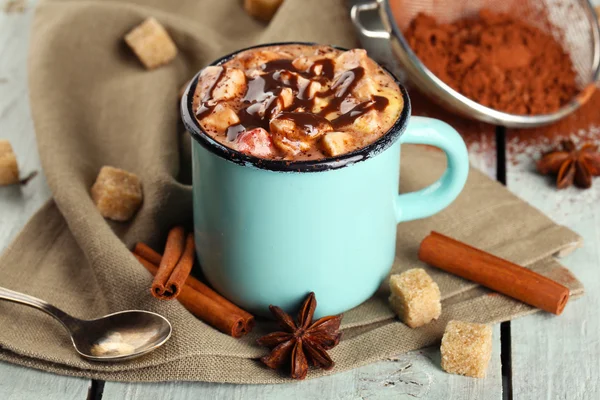 Taza de café caliente con malvavisco en tela con azúcar en bulto, canela, anís estrellado y tinte de cacao sobre fondo de tablones de madera de color — Foto de Stock