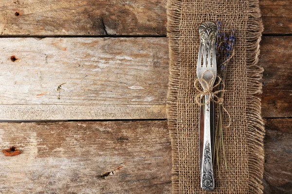 Zilverwerk vastgebonden met touw jute doek en rustieke houten planken achtergrond — Stockfoto