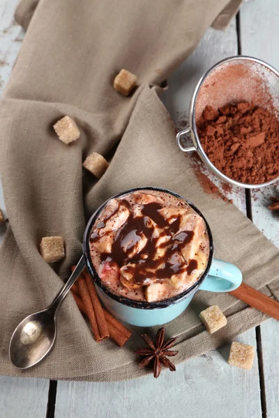 Tasse heißen Kaffee mit Marshmallow auf Stoff mit Klumpen Zucker, Zimt, Sternanis und Kakaofleck auf farbigen Holzplanken Hintergrund — Stockfoto