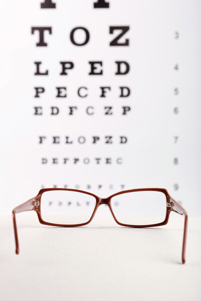 Eye glasses on eyesight test chart background