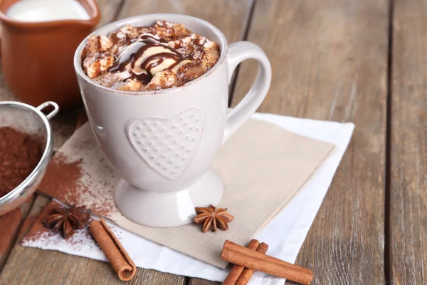 Xícara de café quente com marshmallow e xícara de leite com canela, anis estrelado e coador de cacau em guardanapo e mesa de madeira rústica fundo — Fotografia de Stock