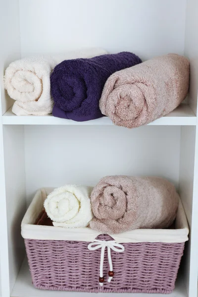 Handdoeken met rieten mand op plank van rack achtergrond rolde — Stockfoto