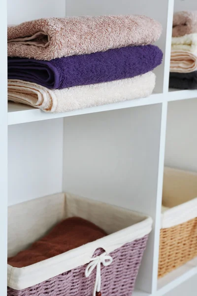 Colorful towels with wicker baskets on shelf of rack background — Stock Photo, Image