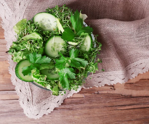 Waterkers salade met gesneden komkommer en peterselie in glazen kom op rustieke houten tafel achtergrond — Stockfoto