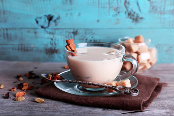 Černý čaj s mlékem a kusový cukr a koření v sklo na barvu pozadí Dřevěná prkna — Stock fotografie