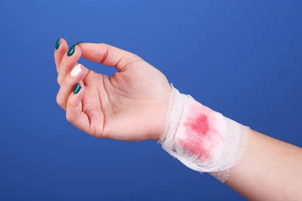 Verletzte Hand mit Verband auf blauem Hintergrund — Stockfoto