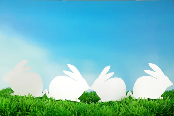 Papíru velikonočních králíků na zelené trávě, na pozadí oblohy — Stock fotografie