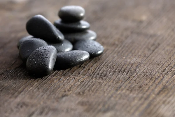 Stack of black sea paddles on rustic wooden background — Stock Photo, Image