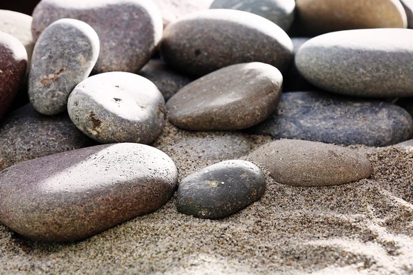 Grijs zee kiezels op zand achtergrond — Stockfoto