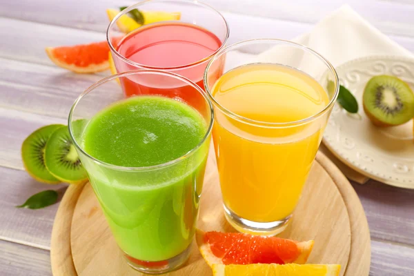Färska juicer med frukter på träbord — Stockfoto