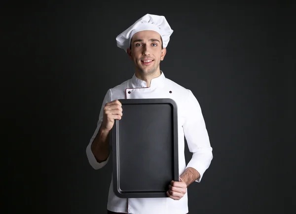 Retrato de chef com panela de forno nas mãos sobre fundo escuro — Fotografia de Stock